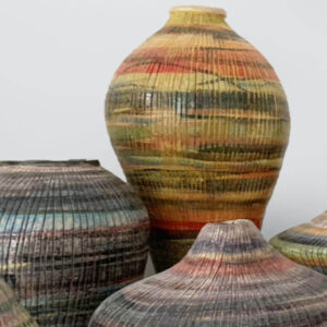 Diverse Keramikvasen, im Fokus ein gelb orange bemalte Vasen